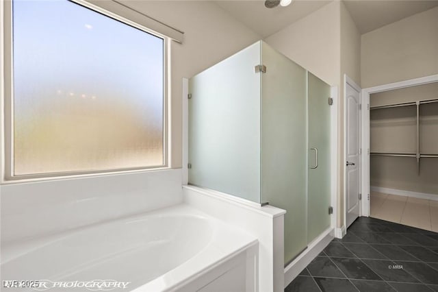 bathroom featuring a stall shower, a walk in closet, a bath, and tile patterned floors