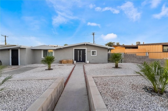 view of front of house with french doors, stucco siding, and fence