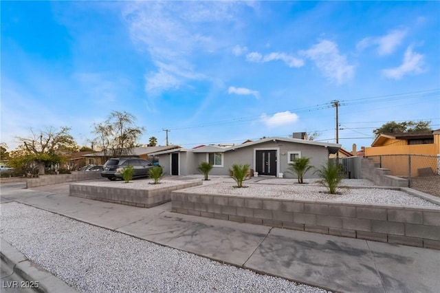 view of front facade with driveway, stucco siding, and fence