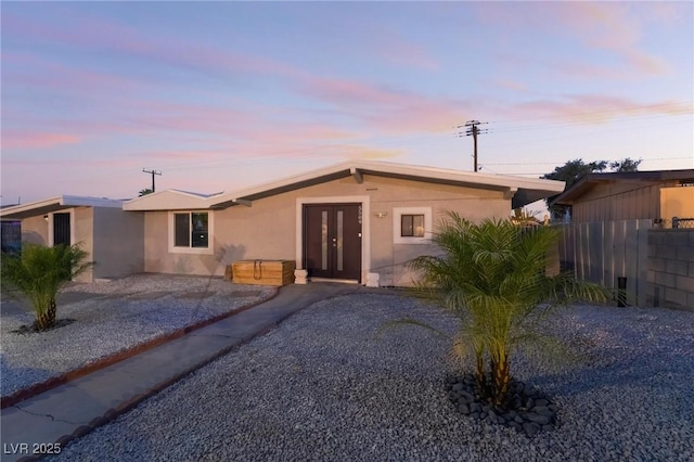 ranch-style home featuring french doors, fence, and stucco siding