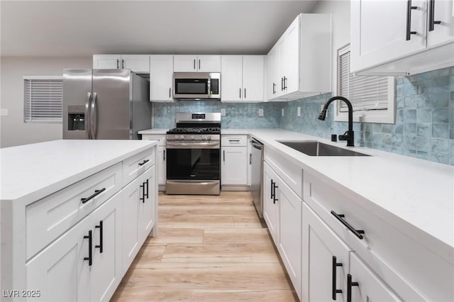 kitchen with a sink, light countertops, stainless steel appliances, backsplash, and light wood-style flooring