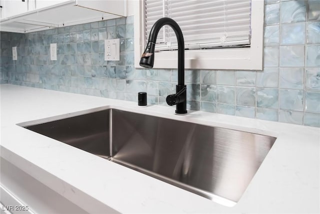 details featuring light countertops, tasteful backsplash, white cabinetry, and a sink