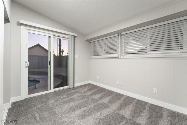 carpeted empty room with baseboards and vaulted ceiling