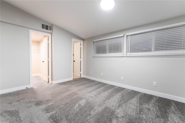 unfurnished room featuring carpet flooring, baseboards, vaulted ceiling, and visible vents