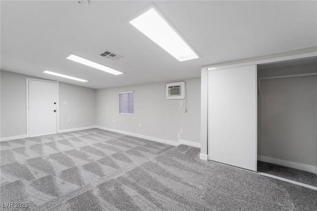 finished basement with carpet flooring, baseboards, an AC wall unit, and visible vents