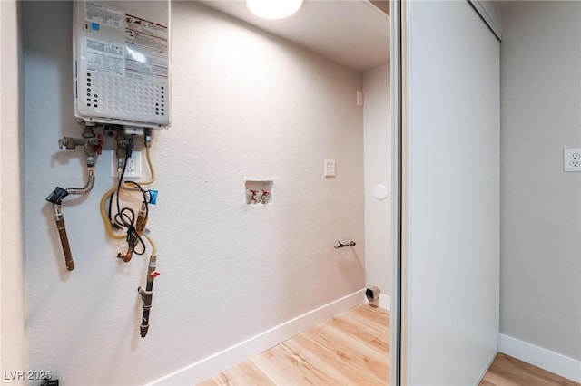 laundry area with laundry area, water heater, wood finished floors, washer hookup, and baseboards