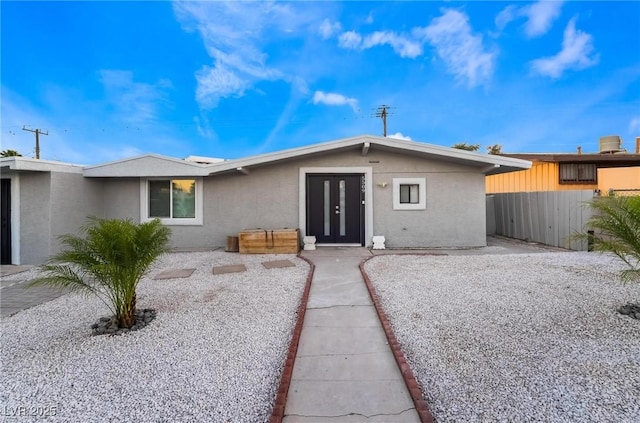ranch-style home featuring stucco siding and fence