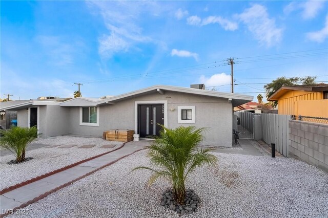 view of front of property featuring a gate, fence, a patio, and stucco siding