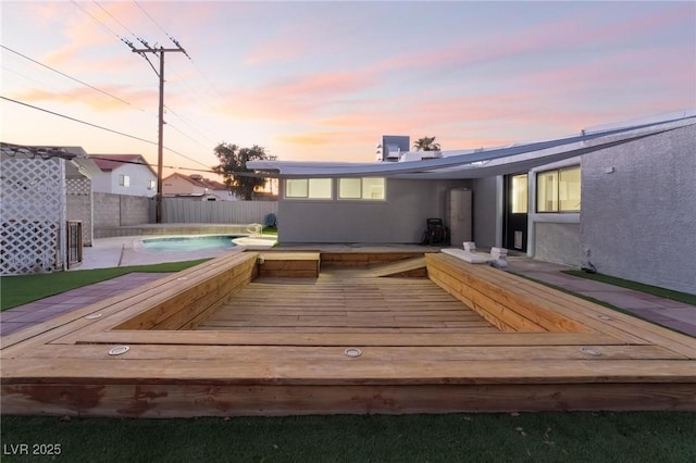 pool at dusk featuring a deck, a fenced in pool, and fence