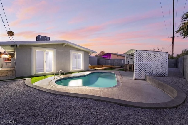 pool at dusk with a fenced backyard, a fenced in pool, a patio, and cooling unit