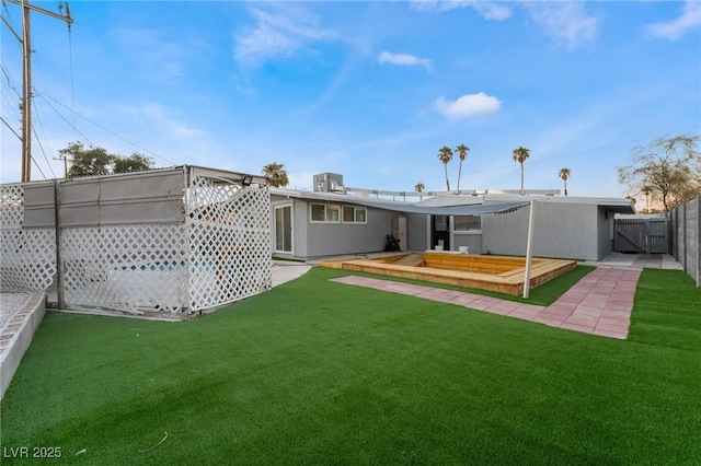 back of property featuring a wooden deck, stucco siding, fence, and a lawn