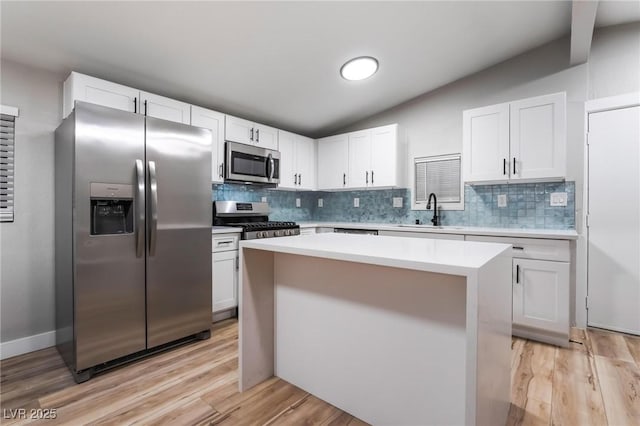kitchen featuring appliances with stainless steel finishes, decorative backsplash, a sink, and vaulted ceiling
