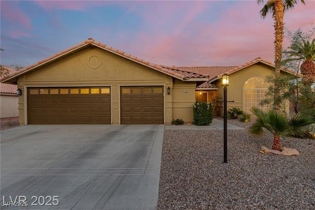 view of front of property with concrete driveway, stucco siding, a tile roof, and a garage