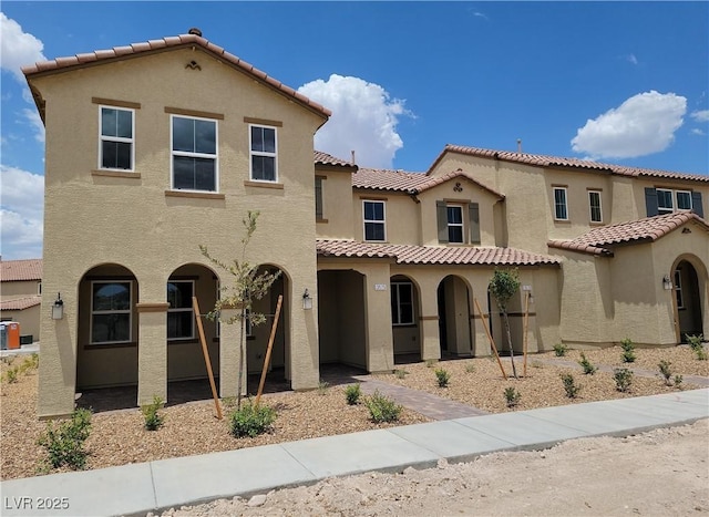 mediterranean / spanish home with a tiled roof, central AC unit, and stucco siding