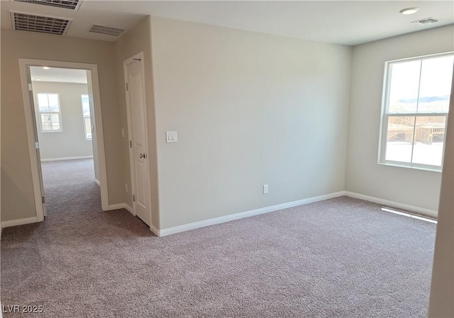 carpeted empty room featuring baseboards and visible vents
