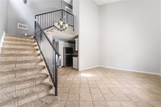 stairs featuring an inviting chandelier, baseboards, tile patterned flooring, and visible vents