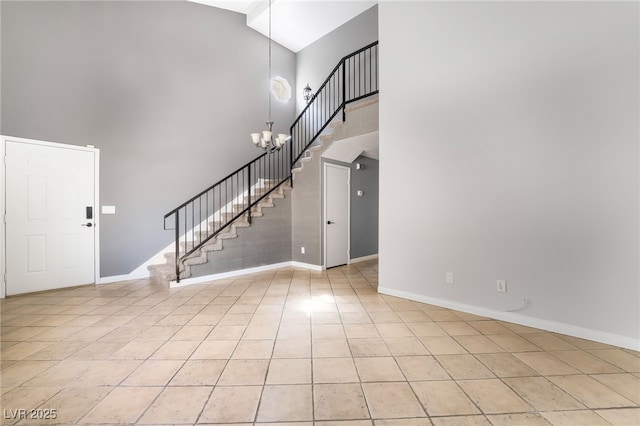 foyer entrance featuring stairs, a high ceiling, baseboards, and light tile patterned flooring
