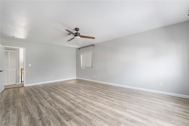 empty room featuring baseboards, a ceiling fan, and wood finished floors