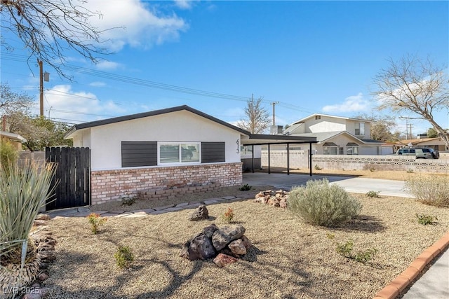 613 Kings Pl, Boulder City, NV 89005 - view of front of house featuring fence, brick siding, stucco siding, a carport, and driveway