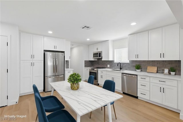 613 Kings Pl, Boulder City, NV 89005 - kitchen with visible vents, white cabinets, tasteful backsplash, a sink, and appliances with stainless steel finishes