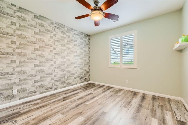 8318 Sonora Del Sol St, Las Vegas, NV 89113 - empty room with baseboards, wood finished floors, ceiling fan, wallpapered walls, and an accent wall