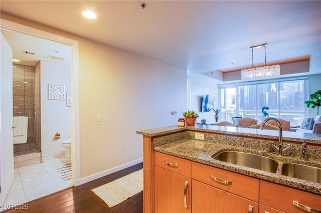 4525 Dean Martin Dr Unit 1103, Las Vegas, NV 89103 - kitchen featuring light stone counters, a sink, baseboards, and brown cabinets