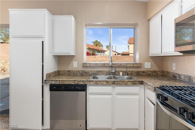 kitchen with white cabinets, tile countertops, appliances with stainless steel finishes, and a sink