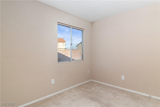 spare room featuring a textured ceiling, carpet flooring, and baseboards