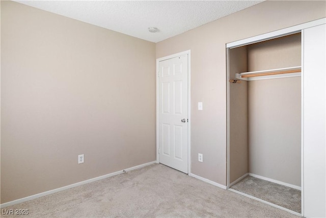 unfurnished bedroom featuring baseboards, carpet floors, a textured ceiling, and a closet