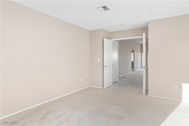empty room featuring visible vents, light colored carpet, and baseboards