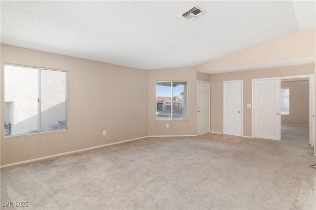 carpeted spare room featuring a textured ceiling, visible vents, lofted ceiling, and baseboards