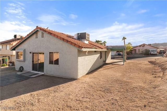 rear view of property featuring cooling unit, a tile roof, stucco siding, and a patio area