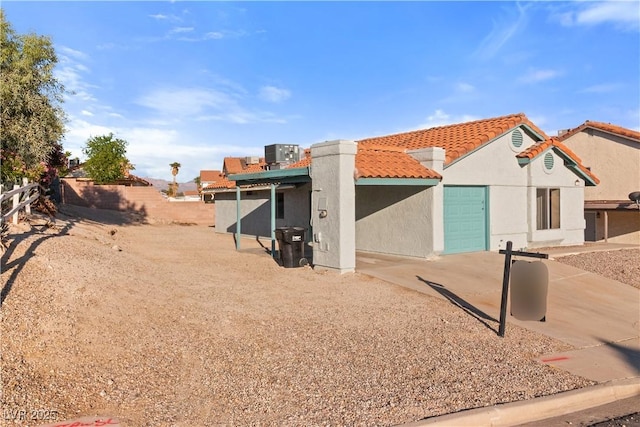 exterior space with a tile roof, fence, an attached garage, and stucco siding