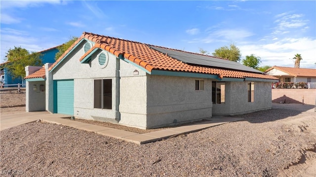 rear view of house featuring roof mounted solar panels, a tile roof, and stucco siding