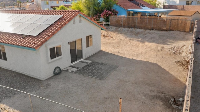 rear view of property with stucco siding, fence, and a tiled roof