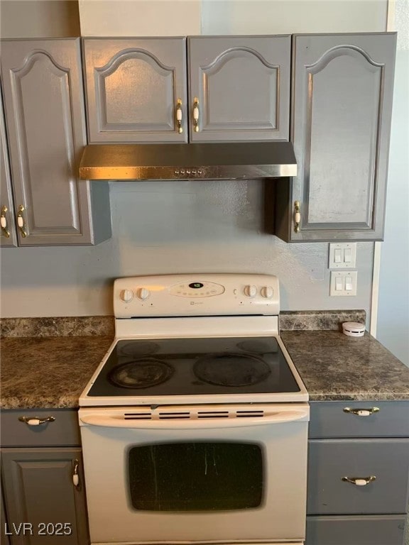 kitchen with gray cabinetry, under cabinet range hood, white range with electric cooktop, and dark countertops