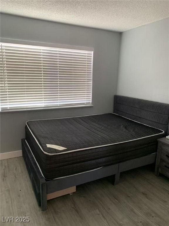bedroom featuring wood finished floors and a textured ceiling
