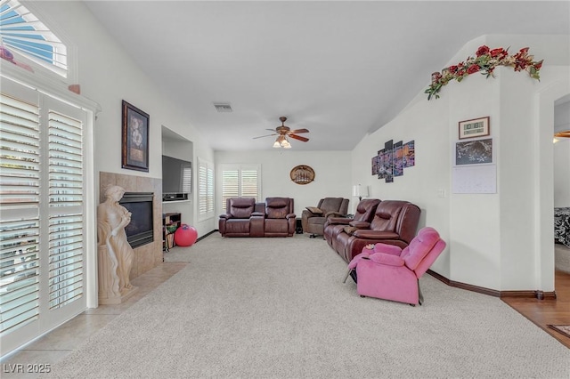 4878 Friar Tuck Ave, Las Vegas, NV 89130 - living room with vaulted ceiling, a tile fireplace, a ceiling fan, light colored carpet, and baseboards
