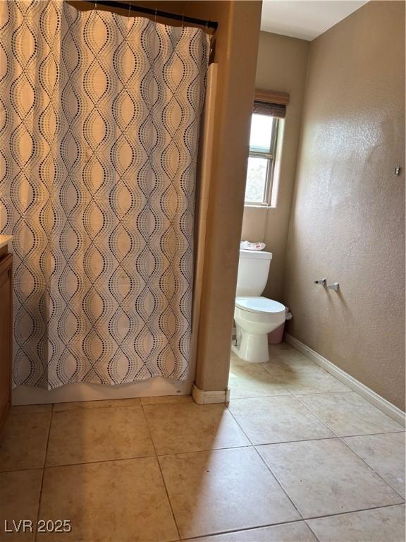 bathroom featuring toilet, tile patterned flooring, baseboards, and vanity
