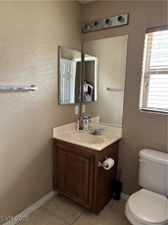 bathroom with tile patterned flooring, vanity, baseboards, and toilet