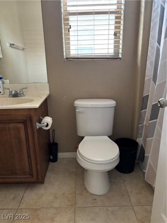 bathroom featuring toilet, vanity, baseboards, and tile patterned flooring