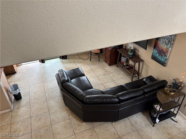 living room with light tile patterned floors, a textured wall, and baseboards