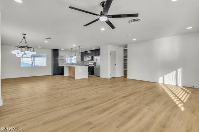 unfurnished living room with recessed lighting, light wood finished floors, visible vents, and ceiling fan with notable chandelier