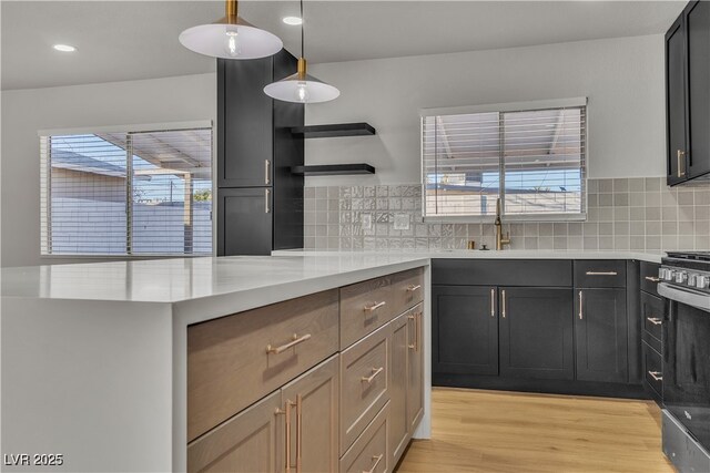 kitchen with light wood-style flooring, light countertops, a sink, and decorative backsplash