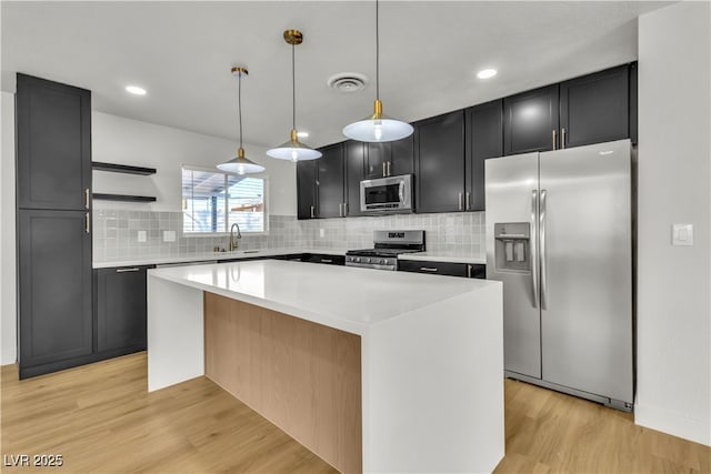 kitchen featuring light wood-style floors, visible vents, a center island, appliances with stainless steel finishes, and a sink
