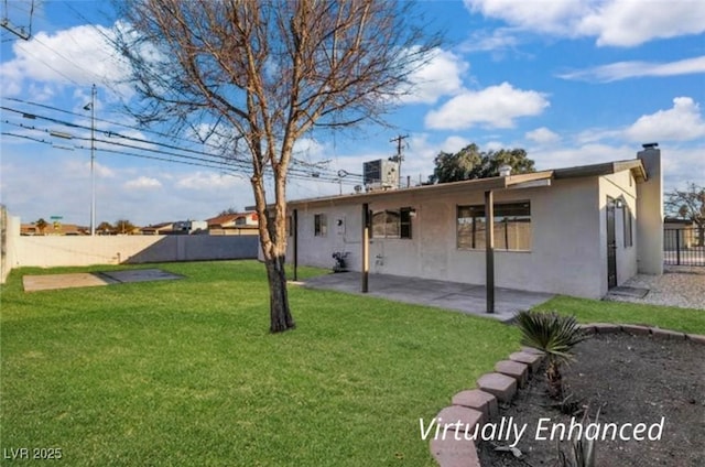 back of property with a yard, stucco siding, a patio, fence, and a chimney
