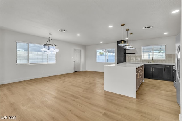 kitchen featuring light wood-type flooring, visible vents, light countertops, and backsplash