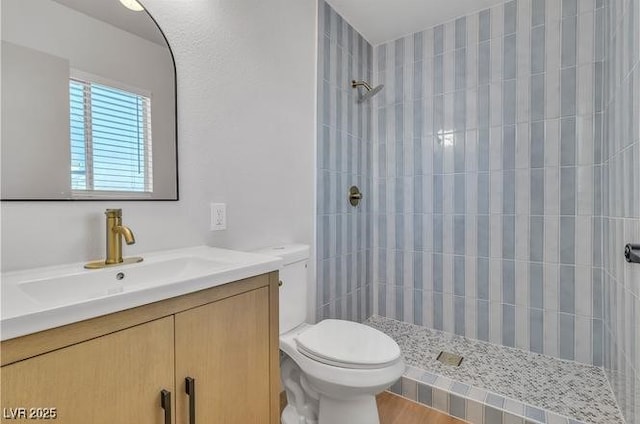 bathroom featuring tiled shower, vanity, and toilet