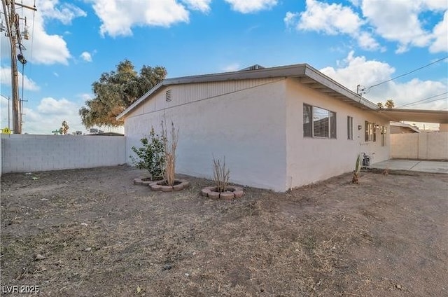 view of side of property with fence, a patio, and stucco siding