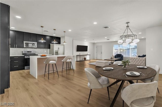 dining room featuring light wood-style flooring, an inviting chandelier, visible vents, and recessed lighting